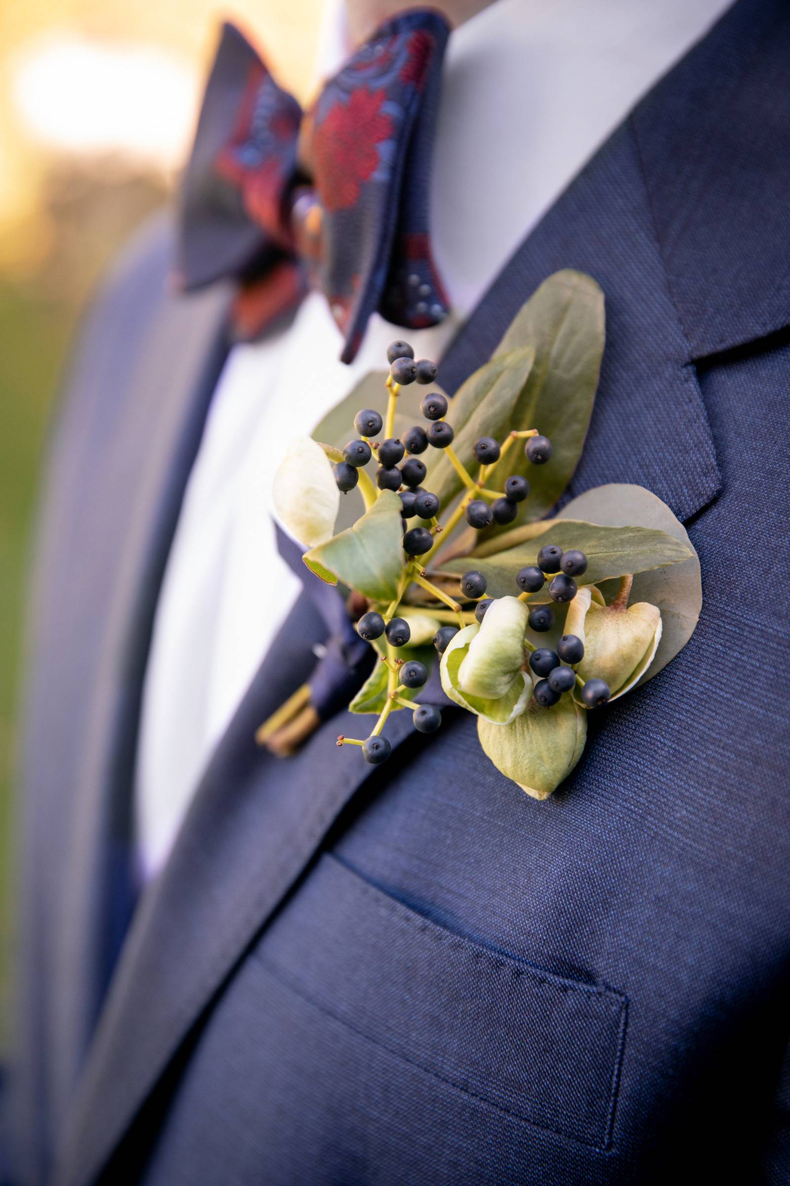 Navy blue groomsmen suits with small green and blue boutonnière for fall Vermont wedding