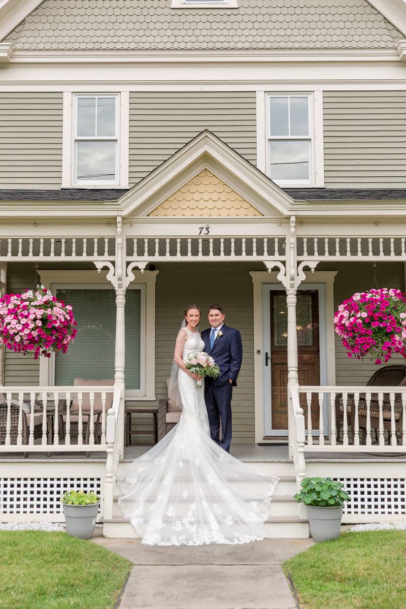 Wedding portrait of couple on front porch with long bridal train