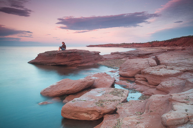 Sandstone rocks at Cavendish Beach with person sitting on top of one of the rocks.