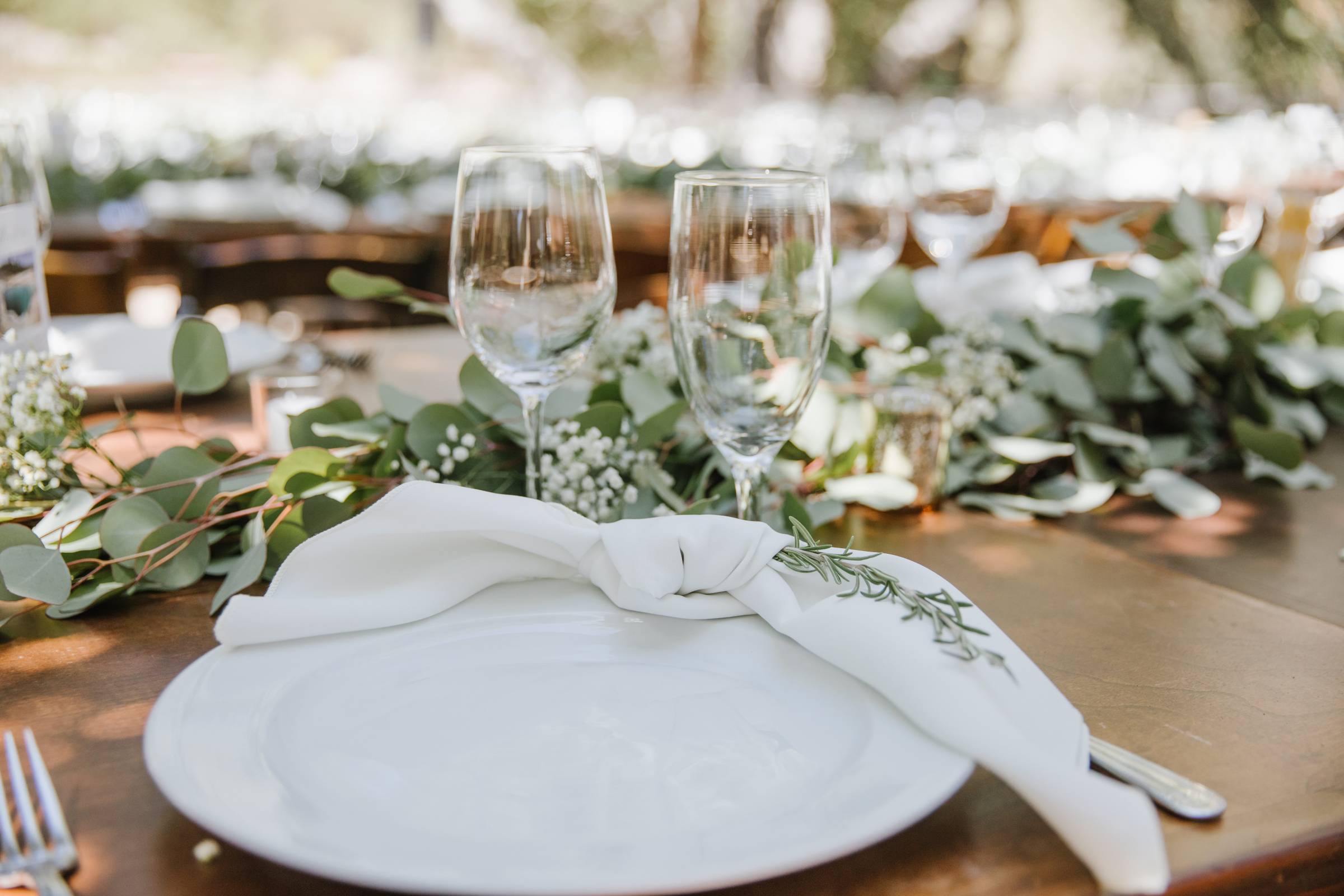 table, place setting, glassware, napkin, plate, greenery