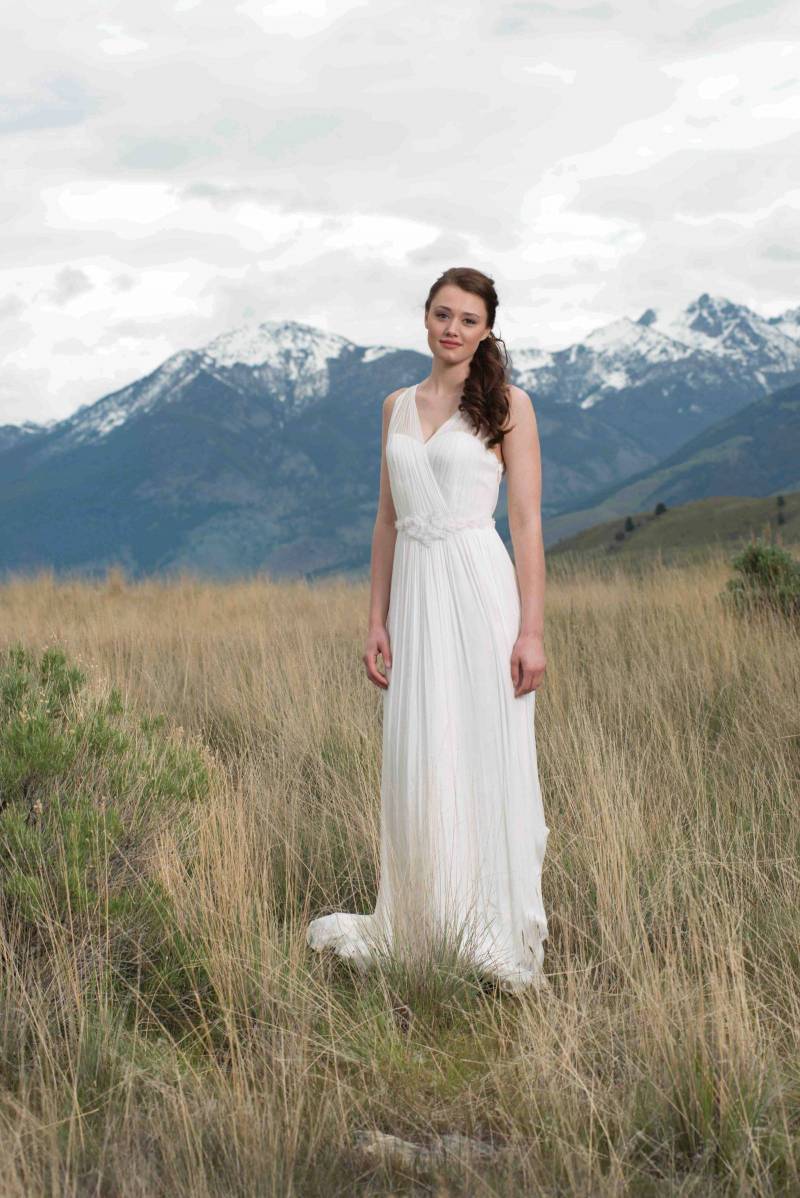 Bride in a flowy off-the-shoulder gown standing in front of mountain backdrop