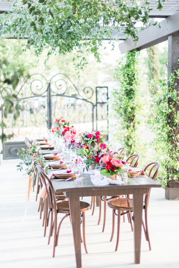 Long wooden tables with pink and burgundy flower arrangements